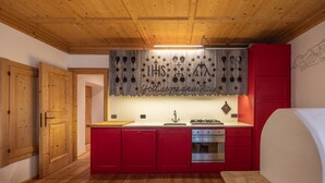 A compact kitchen with wooden cabinets, a countertop, and a stove. - Casa dell'Alpinista in Cortina d'Ampezzo (Cortina d´Ampezzo)
