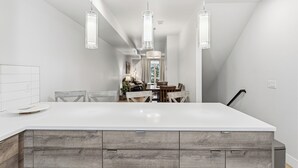 A modern kitchen with a large island, pendant lighting, and a dining area with wooden chairs and a table. - 2BD w/ Rooftop • Minutes to LoHi & Sloan’s Lake (Denver)