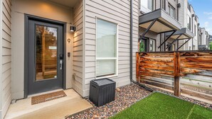 A modern building with a dark front door, a small trash bin, a welcome mat, and a well-maintained lawn. - 2BD w/ Rooftop • Minutes to LoHi & Sloan’s Lake (Denver)