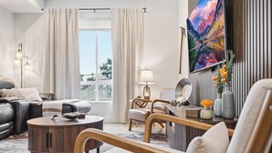 A modern living room with a sofa, armchair, round coffee table, and a painting on the wall. - 2BD w/ Rooftop • Minutes to LoHi & Sloan’s Lake (Denver)