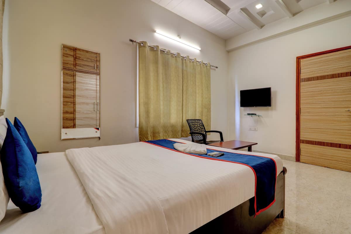 Una habitación de hotel con cama, sillón, televisión y armario.