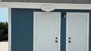 A small building with a sign reading "Laundry Room" and two white doors.
