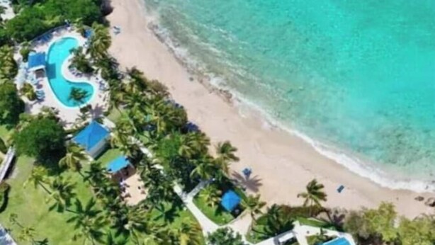Un resort con playa, piscina y varios edificios con techos azules.