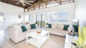 Un salón amplio con techo alto, ventanas grandes y vista al océano.