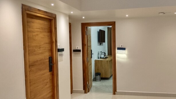 Un couloir avec des portes en bois, un miroir et un interrupteur.