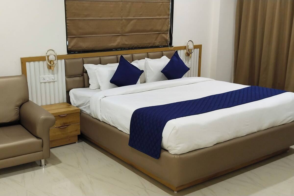 Une chambre à coucher avec un lit, une table de chevet, une chaise et une fenêtre avec des rideaux.
