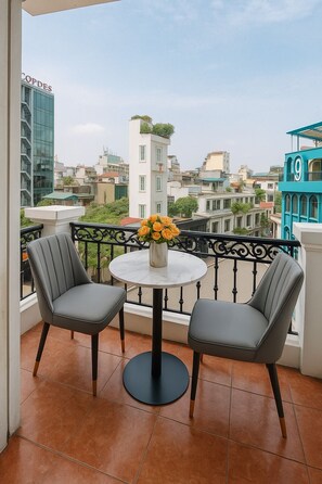 Un balcone con due sedie, un tavolo e un vaso di fiori.