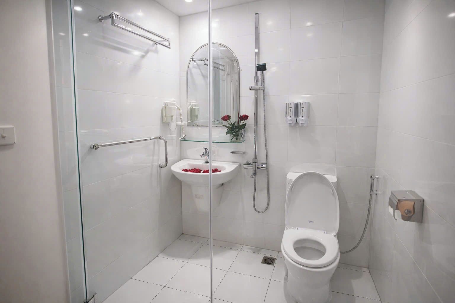 A modern bathroom with a glass shower enclosure, a pedestal sink, and a toilet.