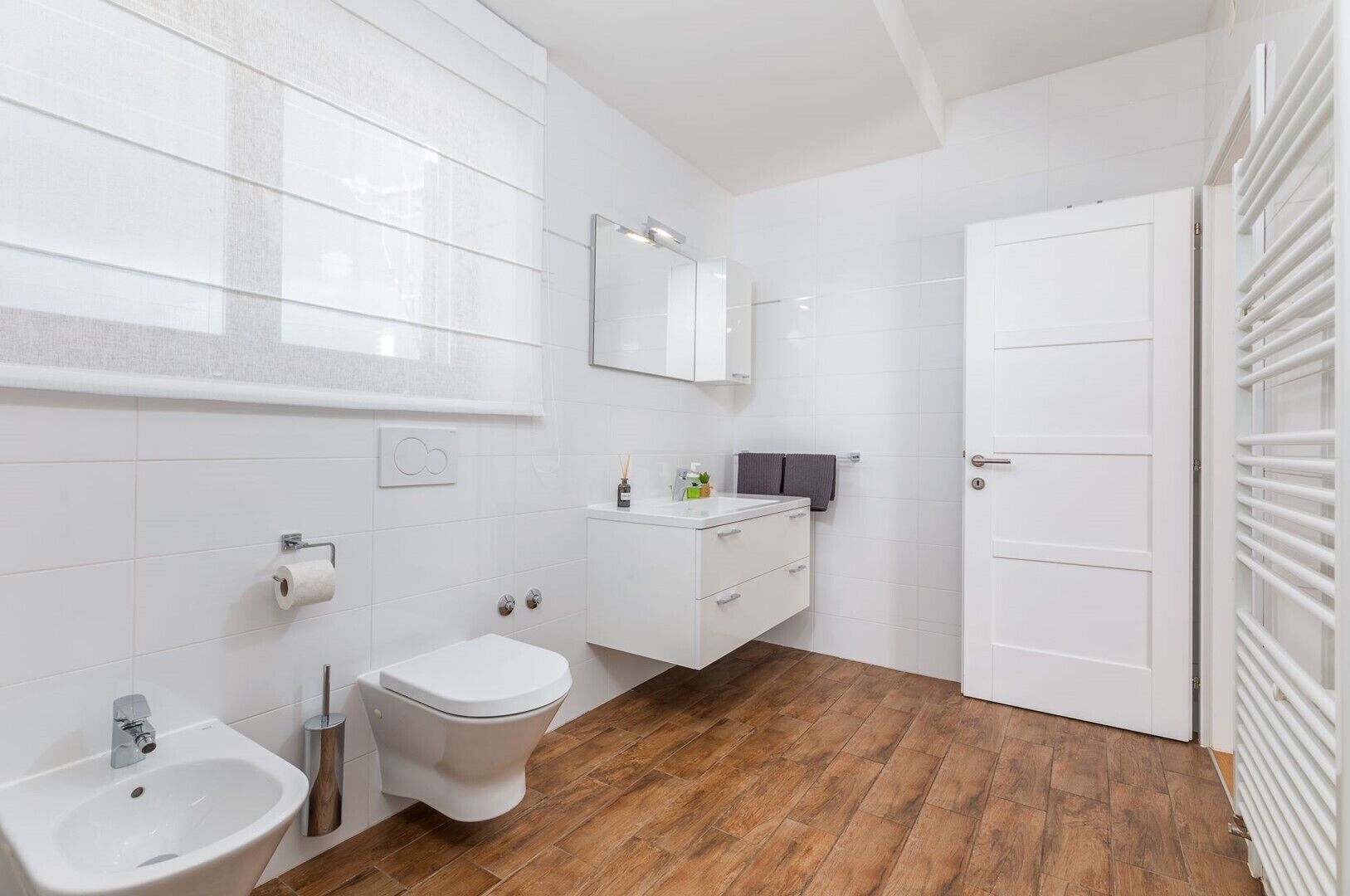 Een moderne badkamer met een toilet, wastafel en een douchetoilet.