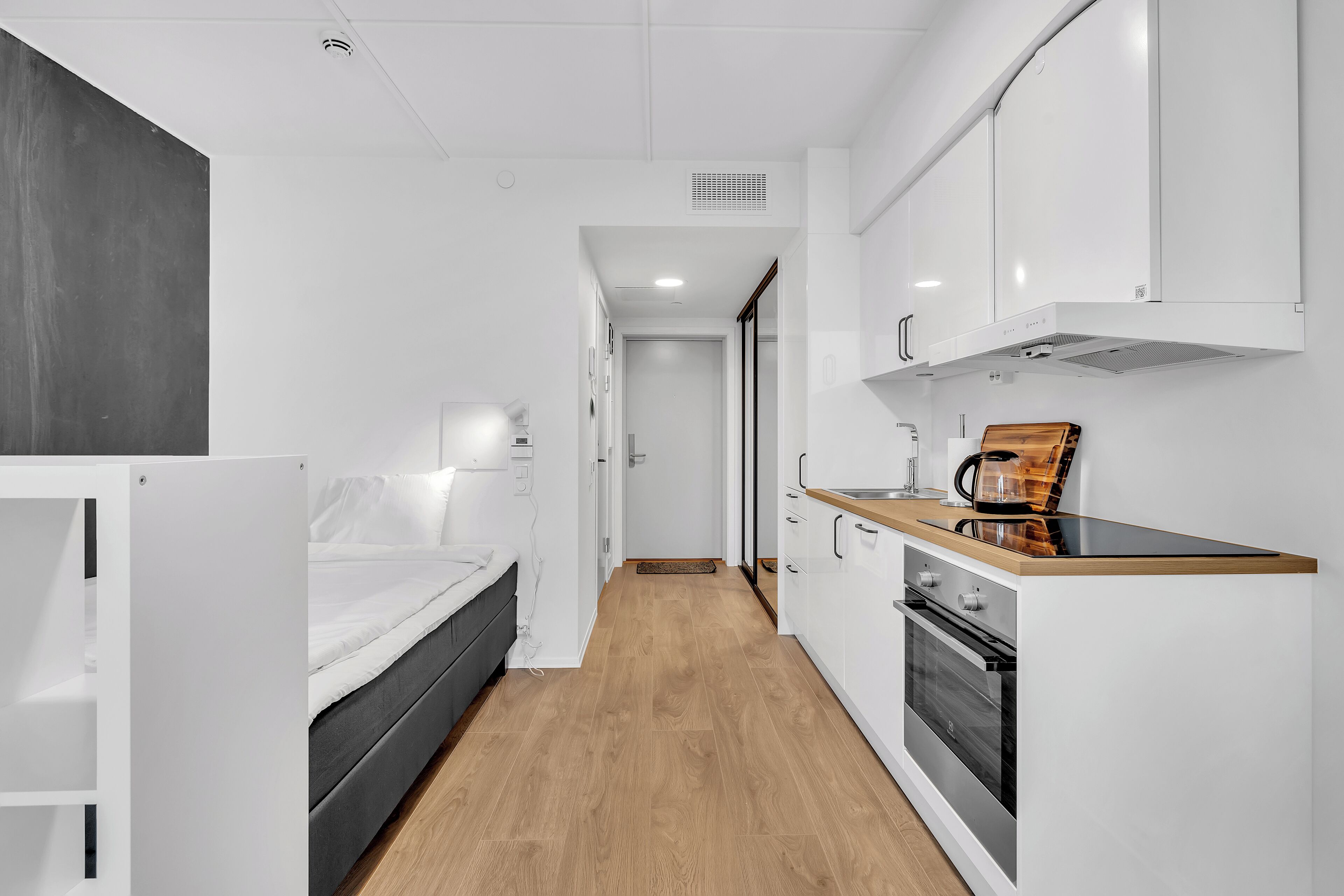 A compact kitchen with white cabinets, a wooden countertop, and a built-in oven.