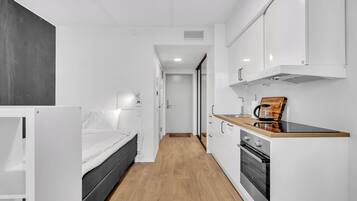 Una cucina compatta con mobili bianchi, un piano di lavoro in legno e un forno integrato.