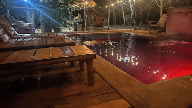 A wooden deck with lounge chairs and a swimming pool at night. - Finca Avellanas  (Tamarindo)