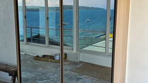 A room with a large sliding glass door leading to a balcony with a view of the sea and boats. - loft rooftop beachfront with an amazing view (Island Garden City of Samal)
