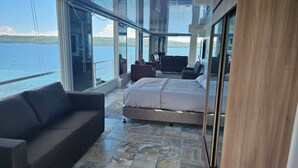 A modern room with a large bed, a sofa, and a view of the water. - loft rooftop beachfront with an amazing view (Island Garden City of Samal)