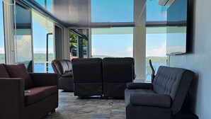 A modern interior with a stone-tiled floor, a large window offering a view of the sea, and a flat-screen TV mounted on the wall. - loft rooftop beachfront with an amazing view (Island Garden City of Samal)