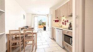 Una cocina moderna con armarios de madera, horno empotrado y lavavajillas. Cuenta con un comedor con mesa y sillas.
