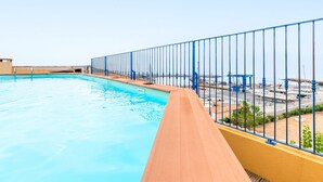 Una piscina con un muelle de madera y una cerca de metal azul.