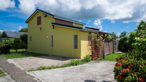 A yellow single-story building with a sloped roof, a small porch, and a gated entrance. - Villa Muscade - Maison avec piscine partagée (Saint-Francois)