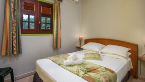 Una cama bien hecha con una colcha floral, un cabecero de madera y una mesita de noche con una lámpara.