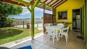 Un patio con piscina, una mesa de comedor con sillas y vista al océano.