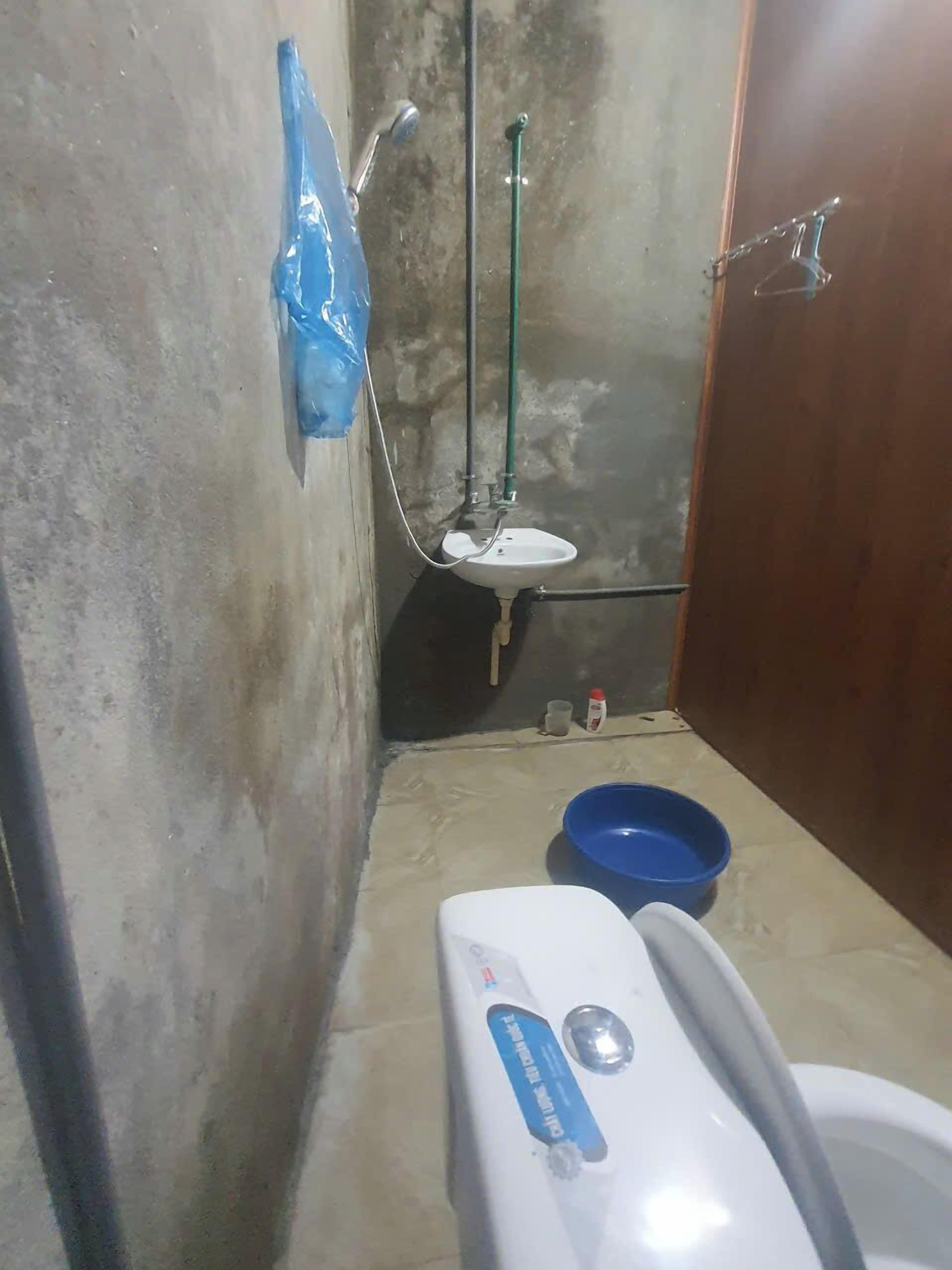 A small bathroom with a white sink, a blue basin, and a toilet.