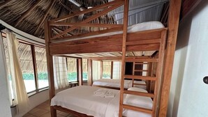 Een slaapkamer met stapelbed, rieten dak, houten wanden en betegelde vloer.