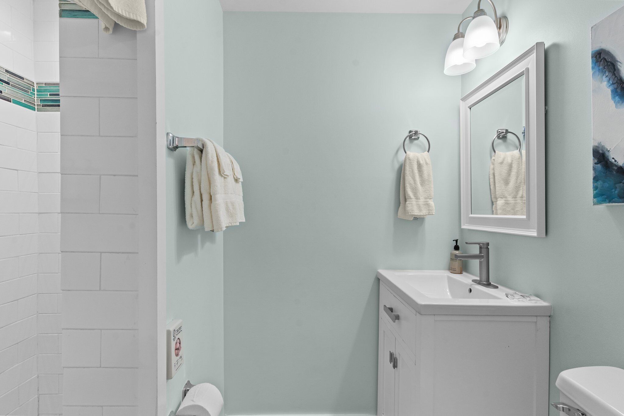 A bathroom with a white sink, a mirror, and two towels hanging on towel racks.