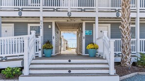 A two-story building with a white exterior, a covered front porch, and a sign indicating an office. - Loggerhead Inn & Suites - King Room in hotel in Surf City, North Carolina (Surf City)