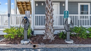 A building with a covered porch, two electric vehicle charging stations, and a palm tree. - Loggerhead Inn & Suites - King Room in hotel in Surf City, North Carolina (Surf City)