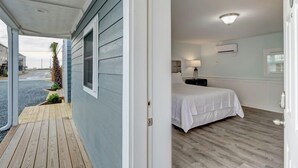 A bedroom with a bed, bedside table, lamp, and an air conditioning unit on the wall. - Loggerhead Inn & Suites - King Room in hotel in Surf City, North Carolina (Surf City)