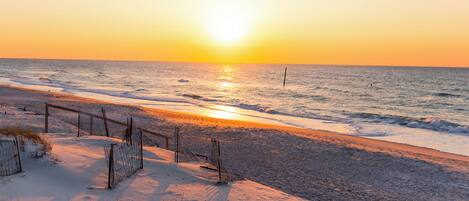 A beach with a fence and sand dunes.