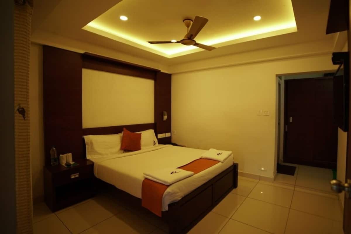 A modern hotel room with a bed, nightstand, ceiling fan, and a door to the right.