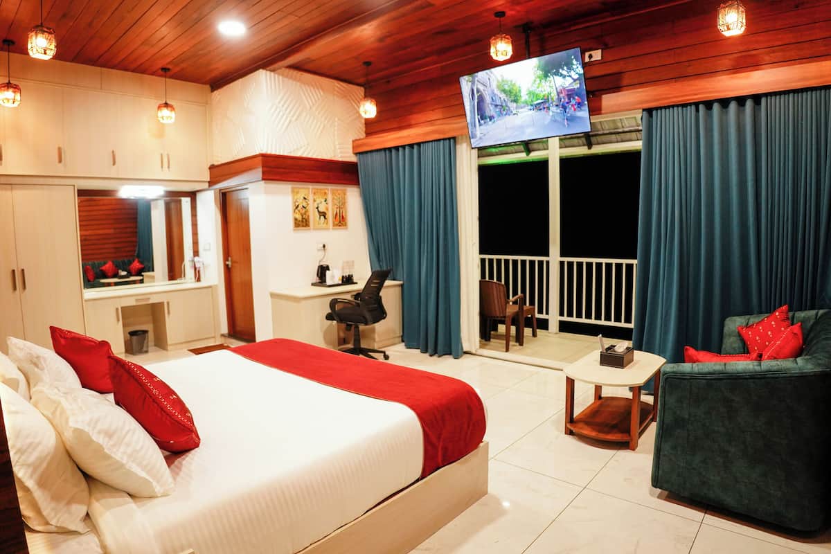 A hotel room with a bed, a desk, a chair, a TV, and a balcony with curtains.