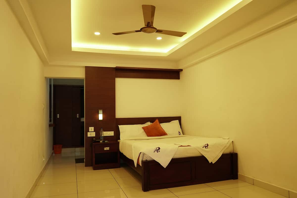 A bedroom with a bed, nightstands, a ceiling fan, and a wall-mounted light fixture.