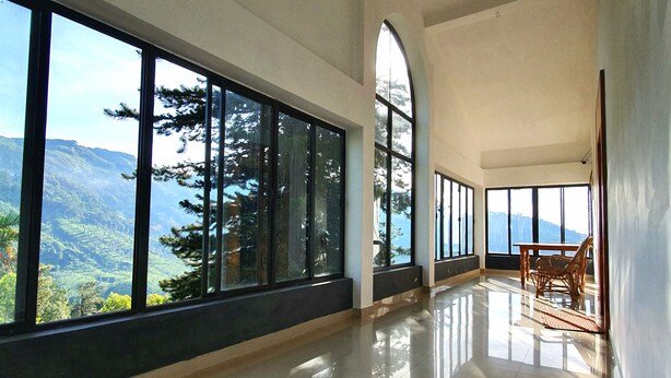 A spacious room with large windows offering a mountain view. - Mount Valley Resort - A Secluded Getaway (Devikolam)