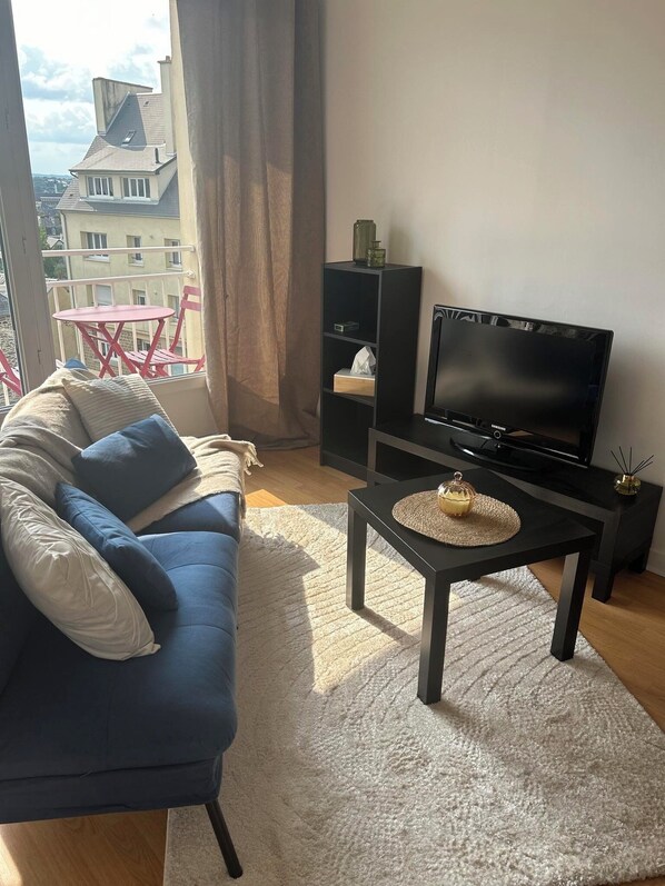A modern living room with a blue sofa, a flat-screen TV, a small coffee table, and a bookshelf. - Bellevue - 35 m² - Parking - 10 min to downtown - Normandy - Saint-Lô (Saint-Lô)