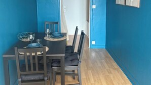 A dining area with a table set for two, two chairs, a bowl, and a wine glass. - "Bellevue - 35 m2 - parking - 10 min downtown - Normandy - Saint Lô (Saint-Lô)