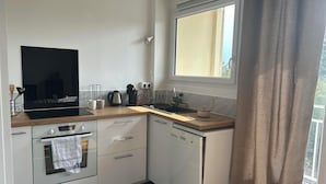 A compact kitchen with a stove, oven, dishwasher, and a window above the sink. - "Bellevue - 35 m2 - parking - 10 min downtown - Normandy - Saint Lô (Saint-Lô)