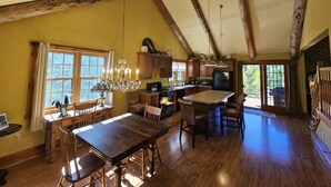 A spacious kitchen with wooden beams, a dining area with a chandelier, and a large island.