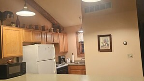Una cocina con armarios de madera, un refrigerador blanco, un microondas y un lavamanos.