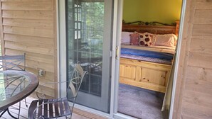 Een kamer met een schuifdeur naar een balkon, een bed met hoofdeinde en een plafondventilator.