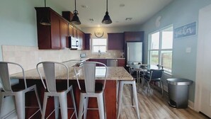 Een moderne keuken met een centraal eiland, barstoelen, hanglampen en uitzicht naar buiten.