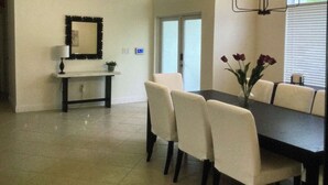 Een eethoek met een donkere tafel, witte stoelen en een kroonluchter.