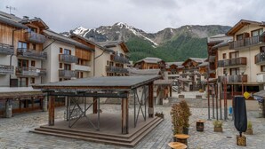 Un village alpin traditionnel, avec des bâtiments en bois, des balcons et une place pavée.