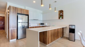 A modern kitchen with a central island, stainless steel appliances, and wooden cabinetry. - Spacious 3-Bedroom Apartment in Fabulous Isla Mujeres (Isla Mujeres)