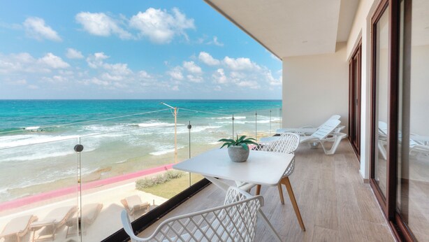 A balcony with a view of the ocean, white furniture, and a potted plant. - Spacious 3-Bedroom Apartment in Fabulous Isla Mujeres (Isla Mujeres)