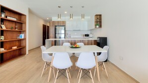 A modern kitchen with white cabinets, a central island, and a dining area with white chairs. - Spacious 3-Bedroom Apartment in Fabulous Isla Mujeres (Isla Mujeres)