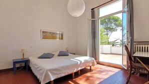 A bedroom with a bed, a nightstand, a table, and a chair. - Charming villa with garden and sea view (Fréjus)