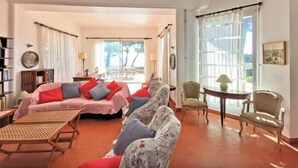 A spacious living room with a sofa set, a coffee table, and a dining area with chairs. - Charming villa with garden and sea view (Fréjus)