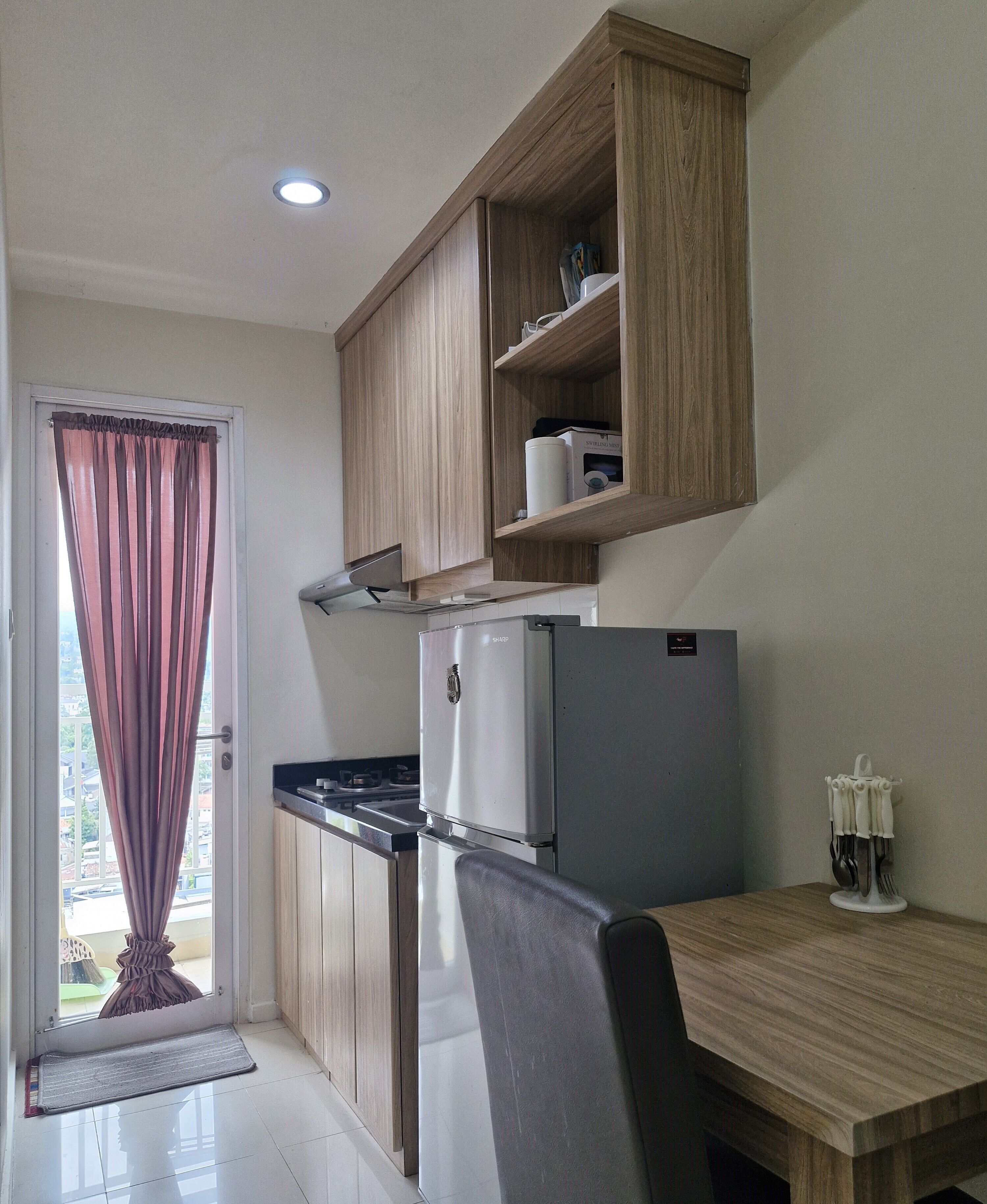 A compact kitchen with a refrigerator, stove, and wooden cabinets.